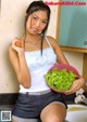 A woman holding a bowl of lettuce and an orange.