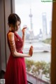 A woman in a red dress looking out a window.