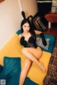 A woman sitting on a yellow couch wearing bunny ears.