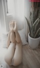 A woman laying on the floor with her feet up next to a plant.