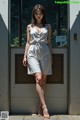 A woman standing in front of a door wearing a white romper.