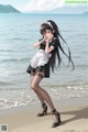 A woman in a maid outfit standing on a beach.