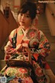 A woman in a kimono sitting on the stairs holding a basket.