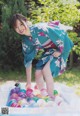 A woman in a blue kimono playing with colorful balls.