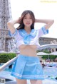 A woman in a blue and white uniform posing by a pool.