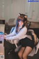 A woman sitting at a desk with a cat ears on her head.