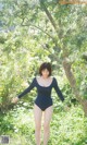 A woman in a black bodysuit standing in the grass.