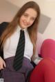 A young woman in a school uniform sitting on a pink chair.