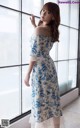 a woman standing in front of a window wearing a blue and white dress