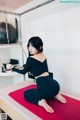 A woman sitting on a yoga mat in a room.